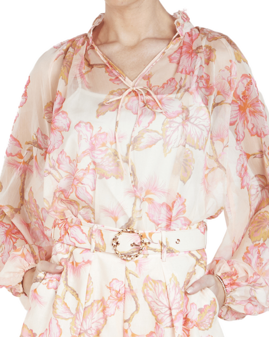 A long-sleeve blouse with a floral print in blush, pink, and peach hues, featuring a neck tie detail.