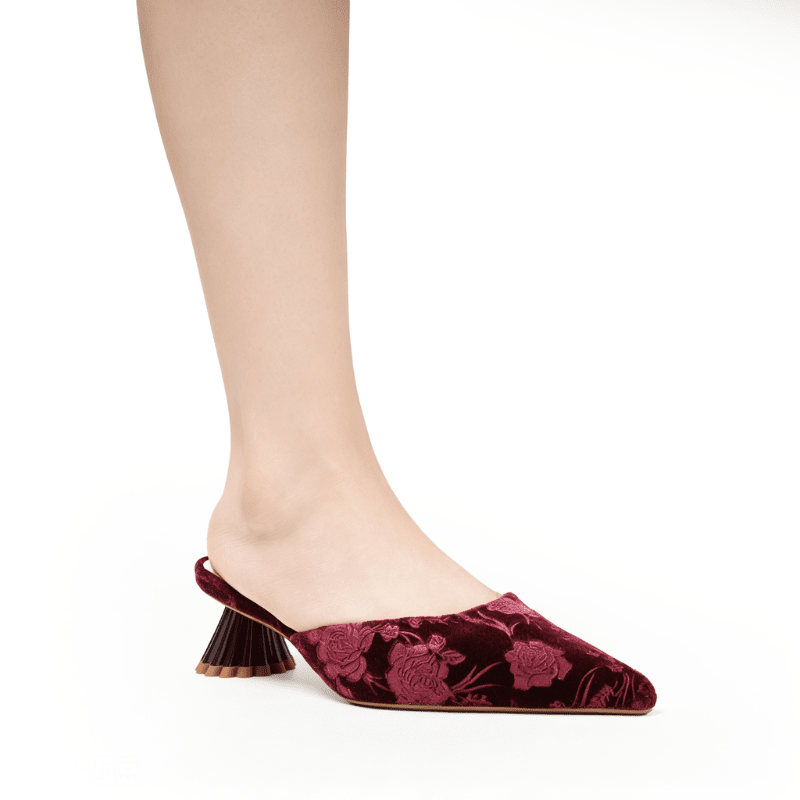 A single women's pointed-toe mule shoe in deep burgundy velvet with a tonal floral jacquard pattern, shown worn on a model's foot against a plain white background.