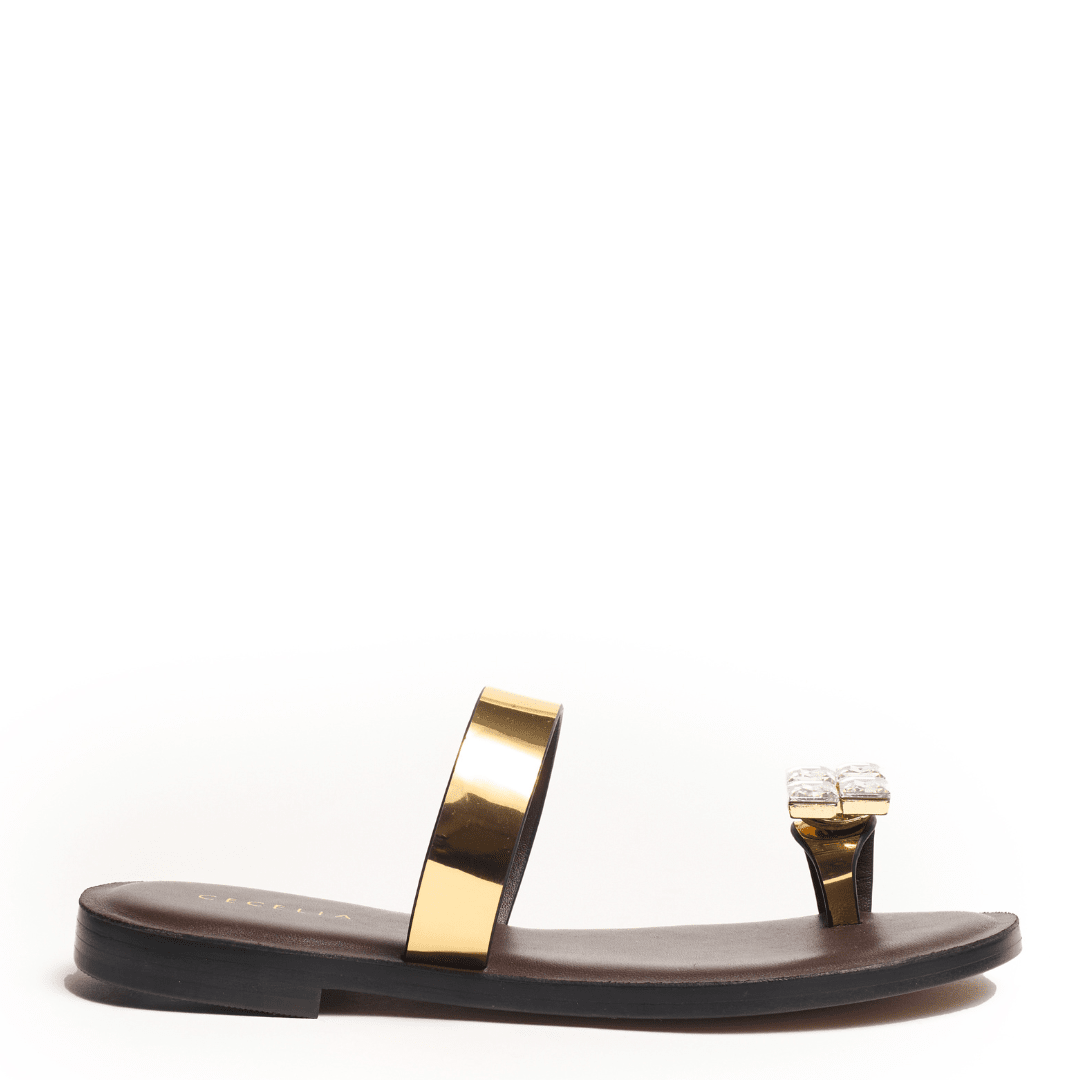 Black sandal with gold strap and decorative toe element