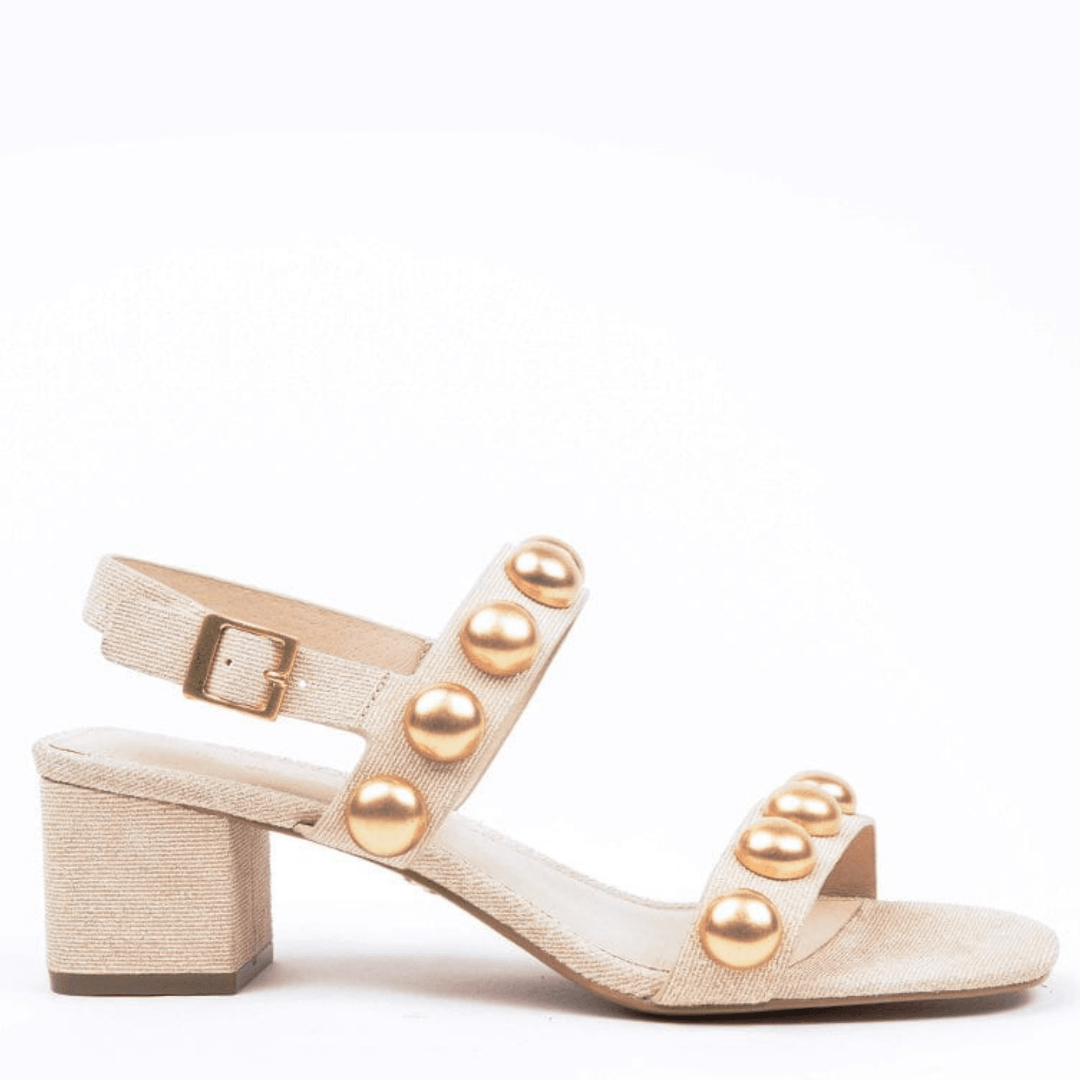 A beige sandal with gold beads, featuring an ankle buckle and a 2-inch heel.