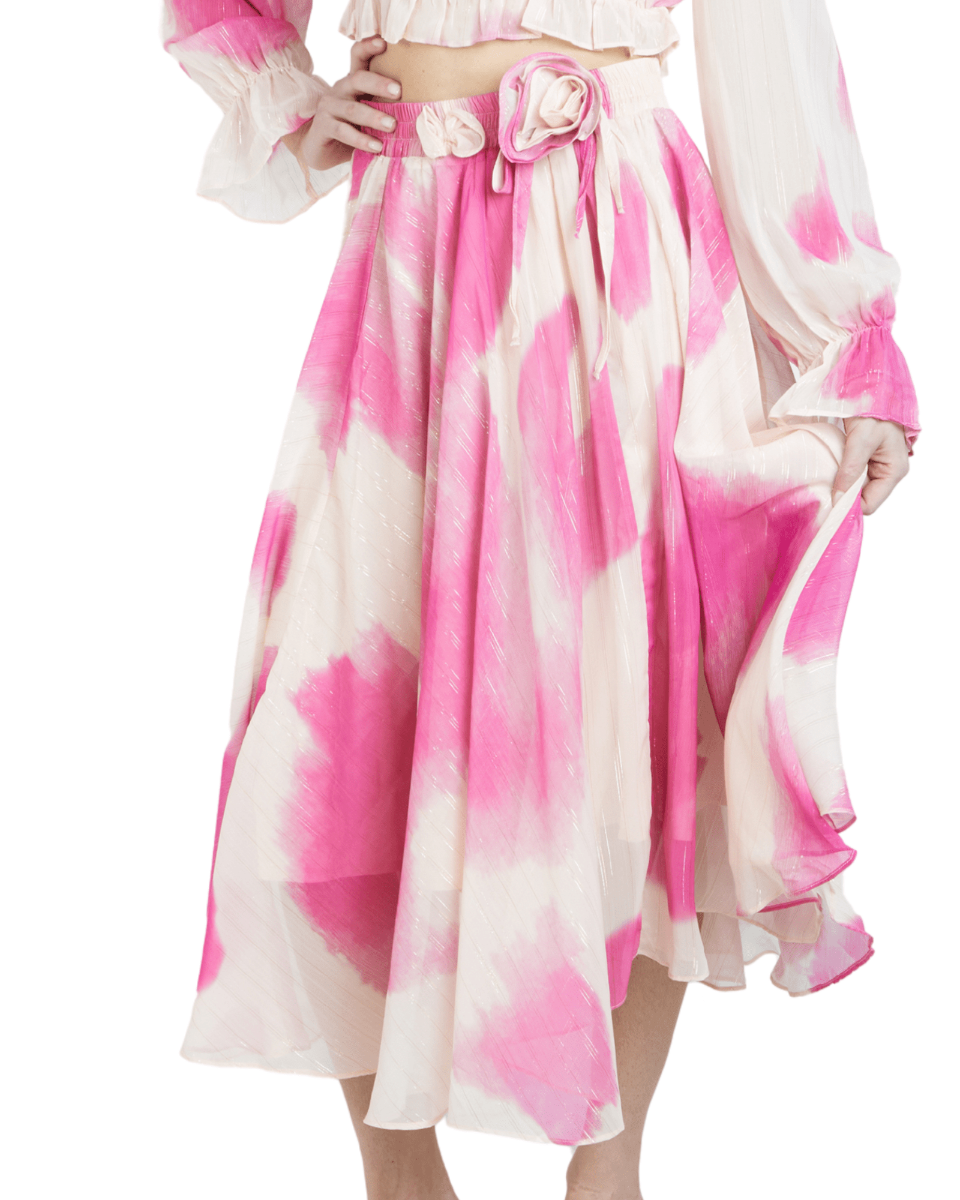 A midi length skirt with a flowy silhouette, featuring a soft ivory base with a delicate pink watercolor print and metallic strands, with an elastic waistband.